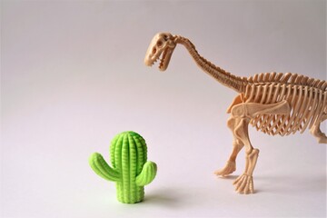 dinosaur skeleton toy next to a cactus, creative photo