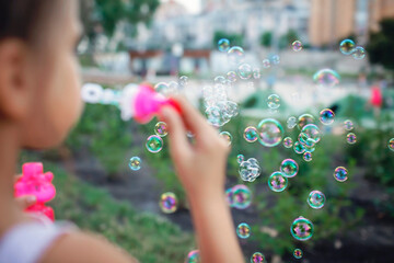 A little girl blowing soap bubbles in summer park, happy childhood, healthy outdoors lifestyle, light and airy, active weekend in the fresh air