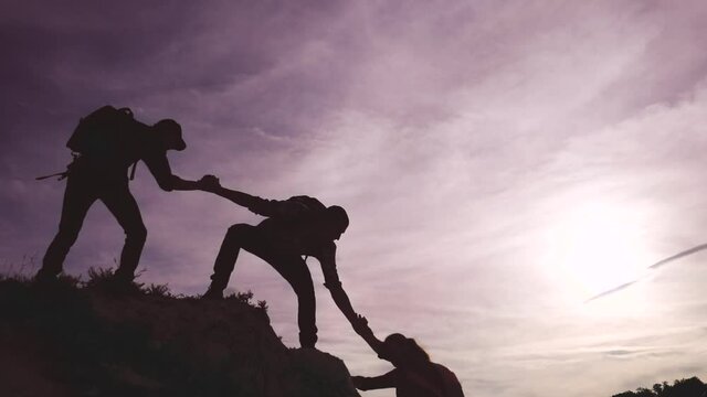 teamwork help business travel silhouette concept. group team of tourists lends a helping hand climb the cliffs mountains. teamwork lifestyle people climbers climb to top lifestyle overcoming hardships