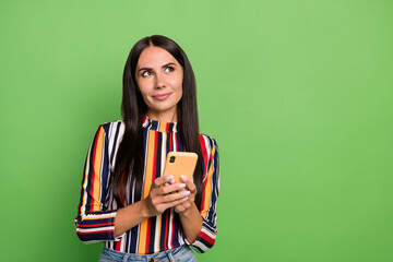 Portrait of attractive minded cheerful girl using device browsing thinking copy space ad isolated over green pastel color background