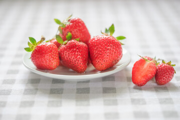 Ripe strawberries in a white plate on the table