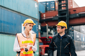 workers teamwork man and woman in safety jumpsuit workwear with yellow helmet  talking at cargo container shipping warehouse. transportation import,export logistic industrial service