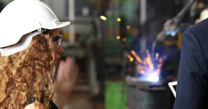 Manufacturing Factory female Mechanical Engineering programer Works on Personal Computer and man worker are working with Robotic Arm at industrial factory
