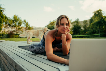 Caucasian female teen working out at home stretching watching videos on laptop