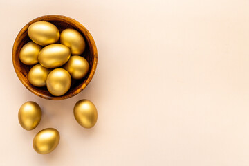 Golden Easter eggs in wooden bowl. Wealth and good luck concept.