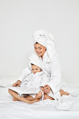 mother and her daughter in white bathrobes read magazines