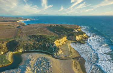 Aerial view of California Pacific coast with beautiful beach and sunny sky, sand, rocks and ocean waves.
