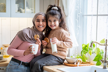 Happy Islamic Mother In Hijab And Little Daughter Having Snacks In Kitchen