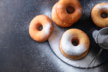 Sweet donuts with powder sugar on black background. Food concept.