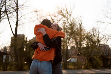 Two teenage skater girls are hugging outdoor.