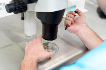 Embryologist or lab technician adjusting needle to fertilize a human egg under the microscope. Doctor adding sperm to egg using microscope. IVF Fertility Lab. Medicine concept.