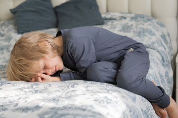Cute blonde boy sleeping in the bed