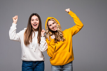 Obraz premium Two young women doing winner gesture celebrating isolated on gray background