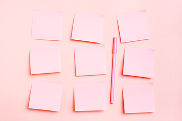 The concept is pink. Blank square small sheets of paper to write in even rows and a pen on a pink background. Top view