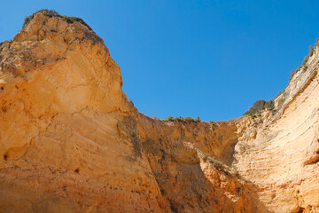 Fototapeta na wymiar beautiful orange rock cliff in Algarve, Portugal against blue sky