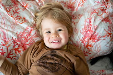 Smiling little boy lying on the bed