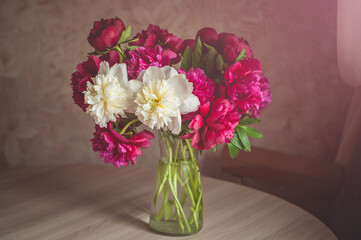 A colorful bouquet of peony flowers in a glass vase