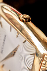 Men's wristwatch with a white dial, gilded case and hands, and a moon phase. Close up with selective focus.