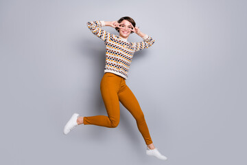 Full length body size view of attractive funny cheerful girl jumping showing v-sign having fun isolated over grey pastel color background