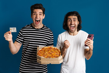 Excited two men using cellphone while holding pizza and credit card