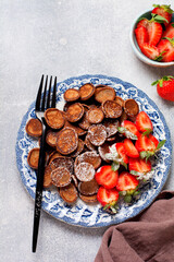 Fototapeta na wymiar Mini chocolate pancake cereal with strawberries for breakfast on gray concrete table. Trendy home breakfast with tiny pancakes. Top view