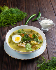 Meat soup with egg in a white plate on a wooden table. Restaurant, menu, recipe. Close-up, front view 