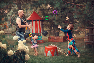 Family portrait in vintage circus style. Father is dressed as a strongman with barbell, son is...