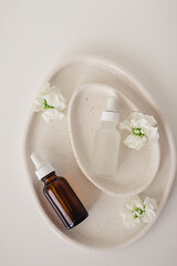 Two amber and matte glass bottles for cosmetics, natural medicine , essential oil inside avocado shaped ceramic plates decorated with flowers on a white background. Top view, beauty product flat lay.