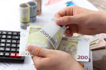 Business financial concept. businessman is looking at financial data on his office desk. Business accounting concept. Counting Money Stack.
