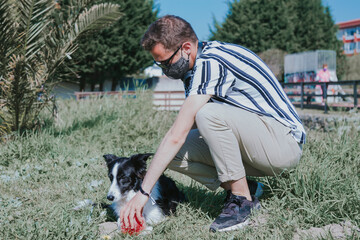 Naklejka na ściany i meble portrait of man with medical mask and his dog in the field