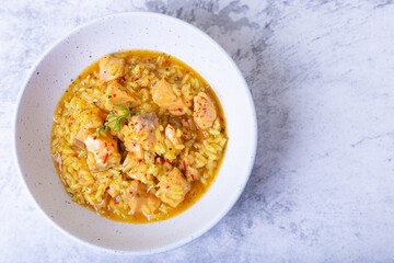 Risotto with salmon and saffron in a white plate. Traditional Italian cuisine. Close-up, top view.