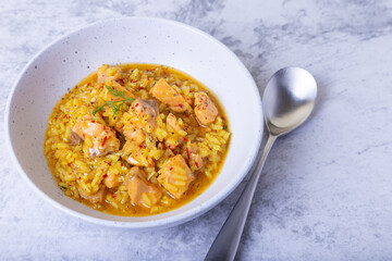 Risotto with salmon and saffron in a white plate. Traditional Italian cuisine. Close-up.