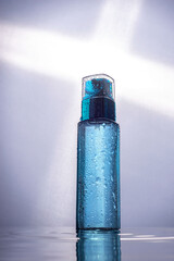 moisturizing the skin. A blue bottle with a liquid for moisturizing the skin of the face, on a white background. advertising photo of cosmetic products for skin care. In a humid environment