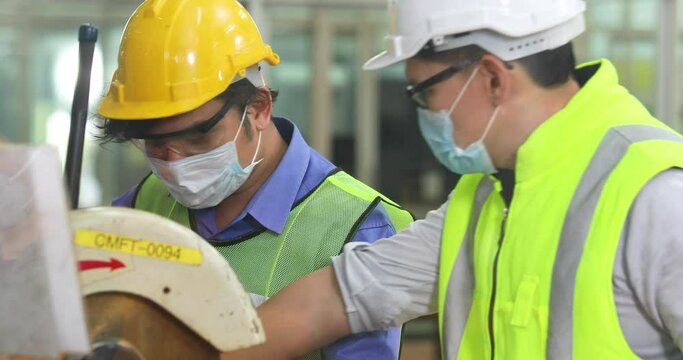Worker man wearing face mask prevent covid-19 virus and protective hard hat. Engineer Operating lathe Machinery.