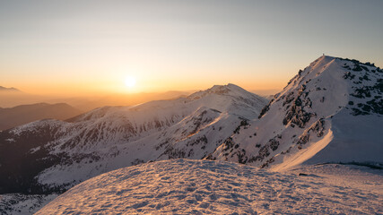 Morning view of the peak of the snow-covered Chopok mountain and the Low Tatras mountain range on a sunny day in the ski resort Jasna, Slovakia. Sunset 