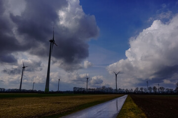 long wet road with wind turbines and clouds after rain