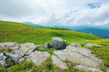 alpine mountain scenery in summer. cloudy weather. stones and boulders on grassy hills and meadows. beautiful view in to the distance