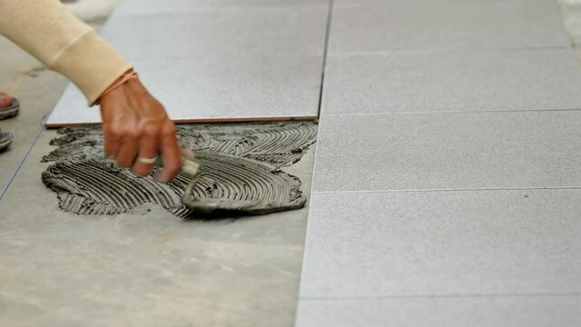 Worker putting tile glue on concrete floor