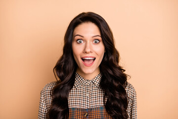 Portrait of pretty cheerful amazed wavy-haired girl wearing checked shirt great news reaction...