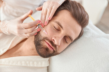 Close up makes mesotherapy injections to young man. Treatment of male by a beautician for...