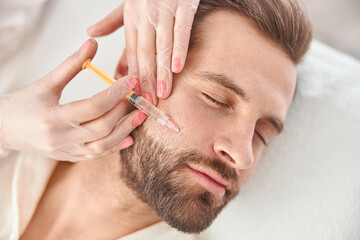 Close up makes mesotherapy injections to young man. Treatment of male by a beautician for...