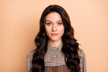 Portrait of pretty calm content wavy-haired girl wearing checked uniform isolated over beige pastel color background