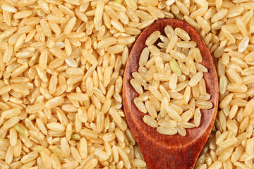Close up of whole grain brown rice with wooden spoon