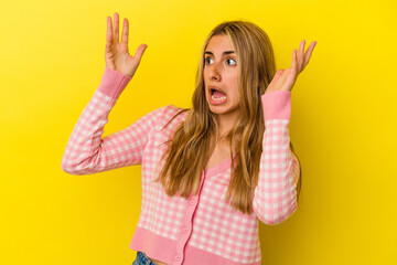 Fototapeta na wymiar Young blonde caucasian woman isolated on yellow background screaming to the sky, looking up, frustrated.