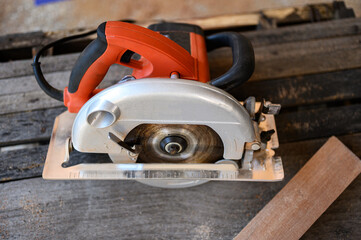 Electric circular saw with steel toothed disc put on the wooden table for ready to repair or renovate something.