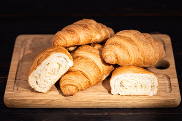 fresh croissants on wooden board on a dark background