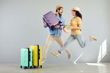 Summer vacation hype. Happy overjoyed young caucasian family couple jumping with travel accessory...