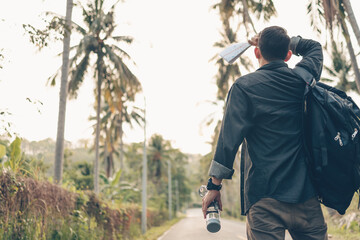 A man with backpack hiking wipe the sweat and hold the water bottle on the road in forest. Backpack travel concept.