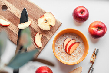 Tasty oatmeal with apple pieces in yellow bowl on the table. Top view. Healthy diet breakfast