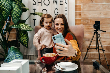 Blogger mother and her little daughter have fun together with the vlog camera. Young parenting...